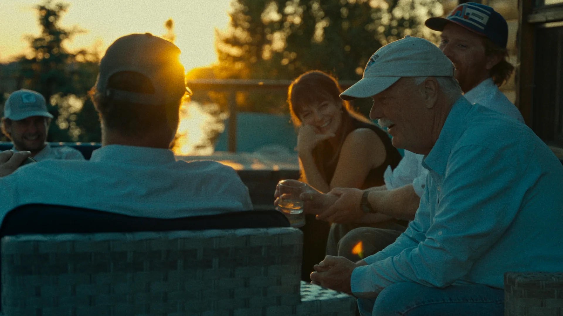 Guests talking around a table on the deck at sunset