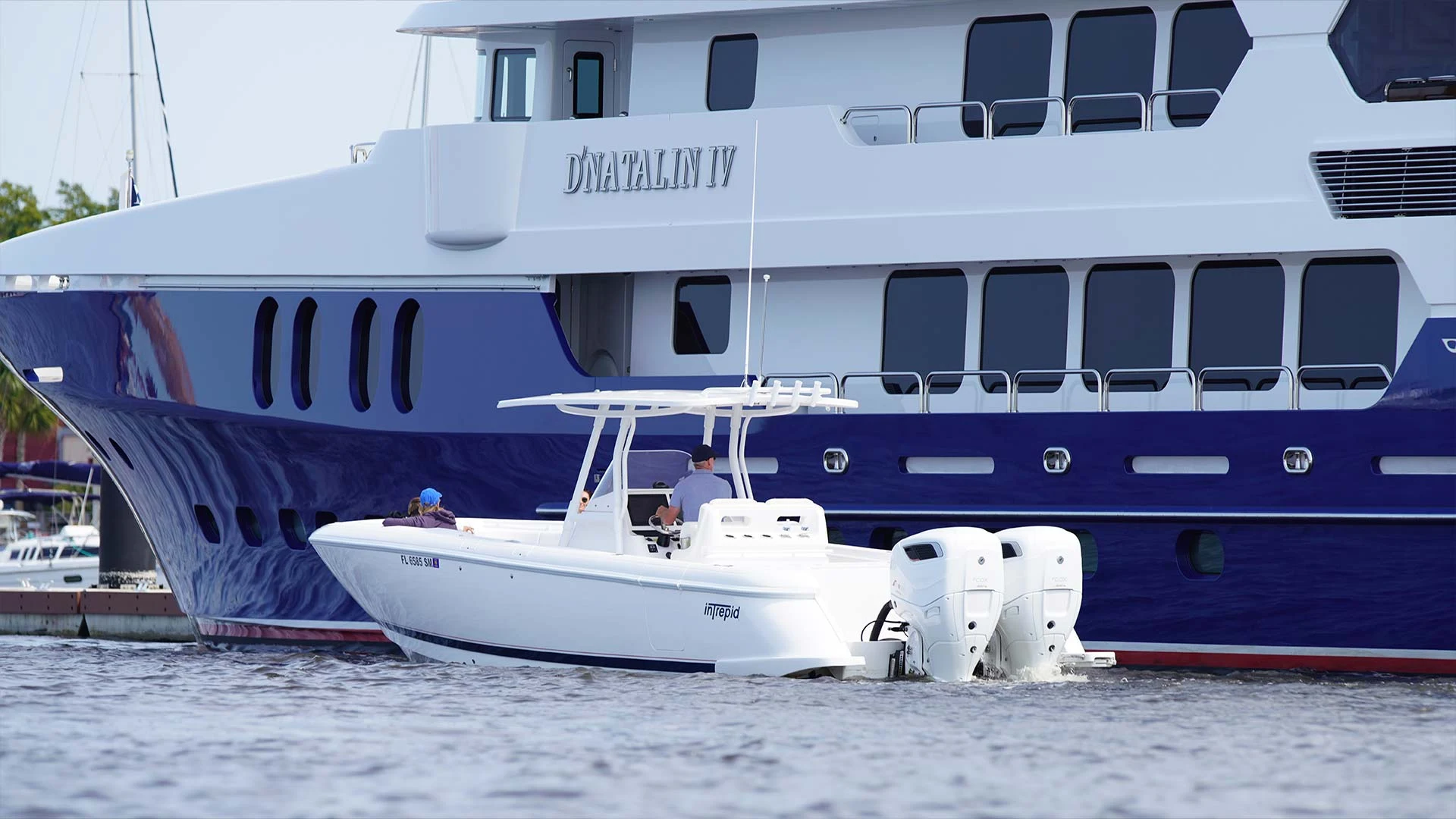 A Cox-powered center-console boat alongside a large motor yacht