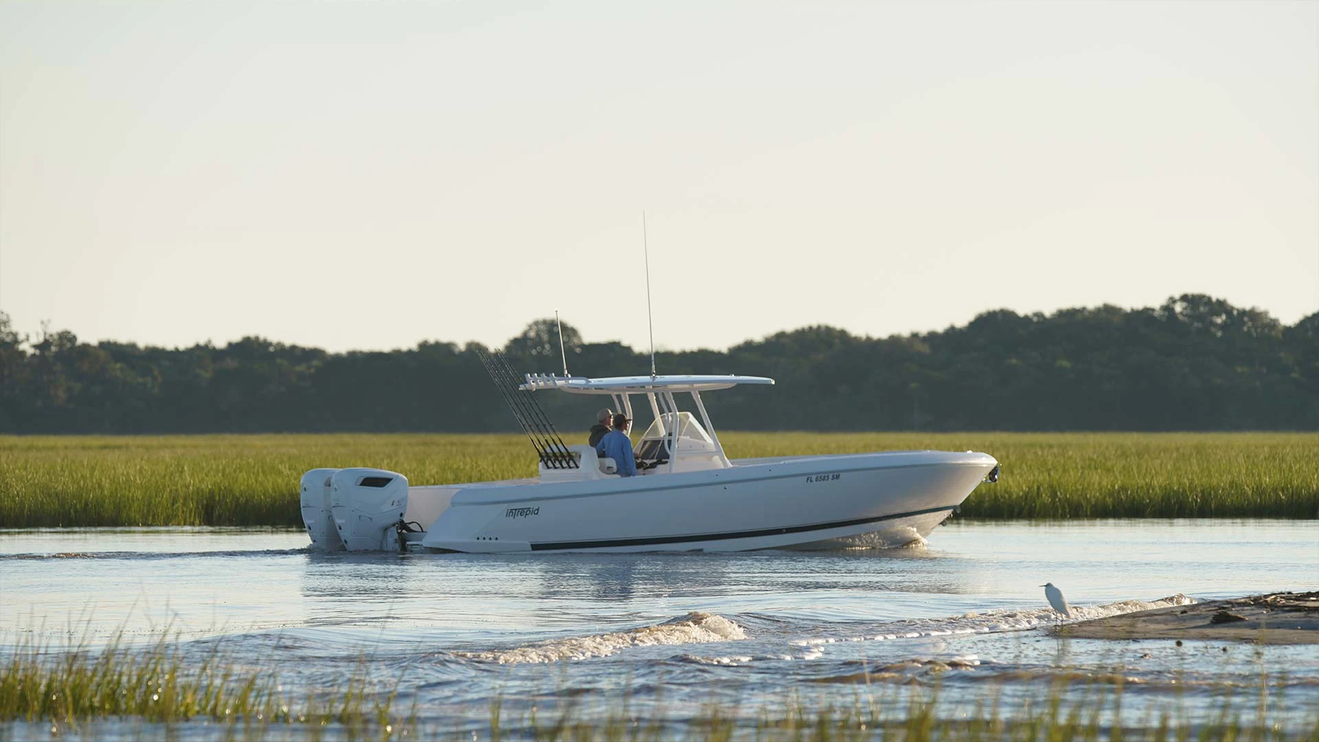 A Cox-powered boat running alongside a salt marsh