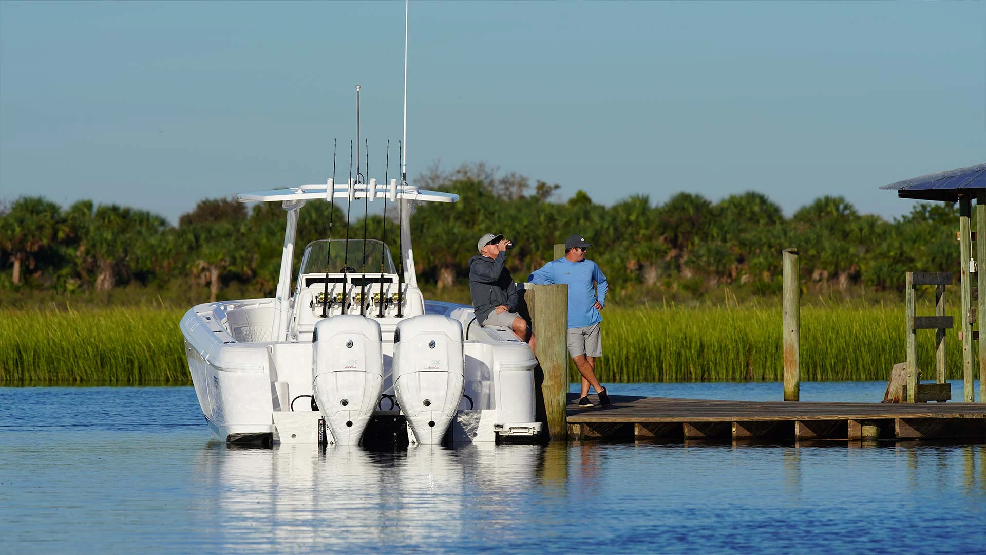 A Cox-powered boat alongside a dock with people aboard and ashore