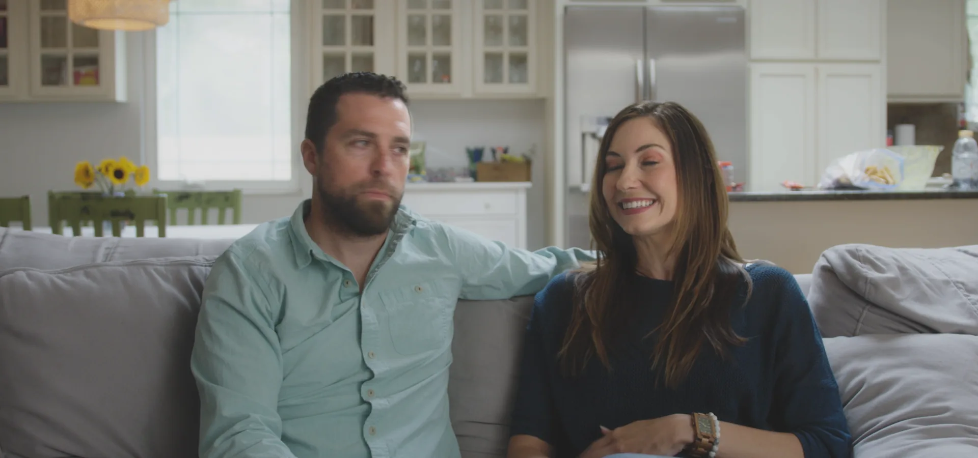 A couple laughing together on their sofa, from the Portability story