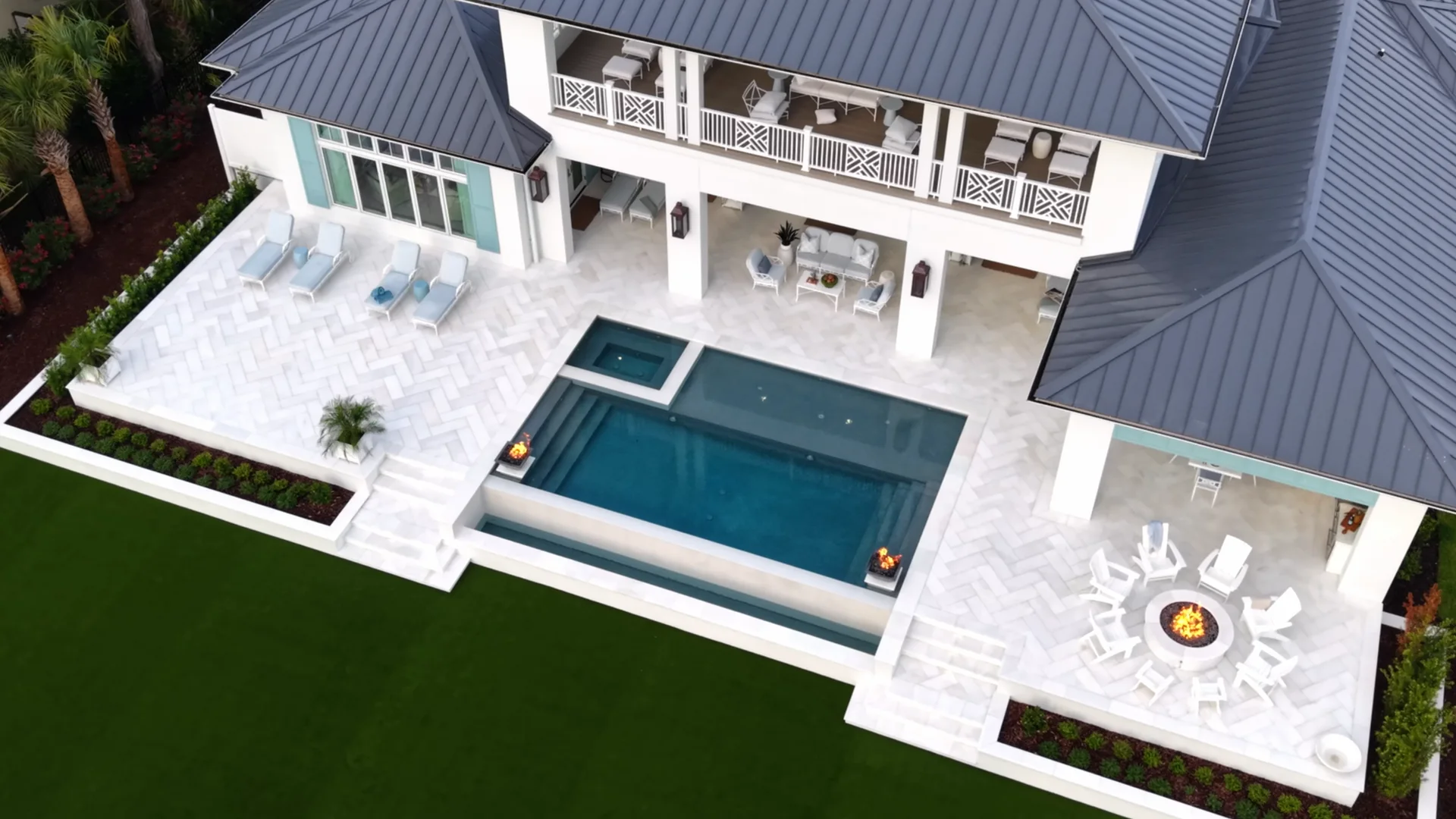 Aerial view of a waterfront home, pool, and patio by day