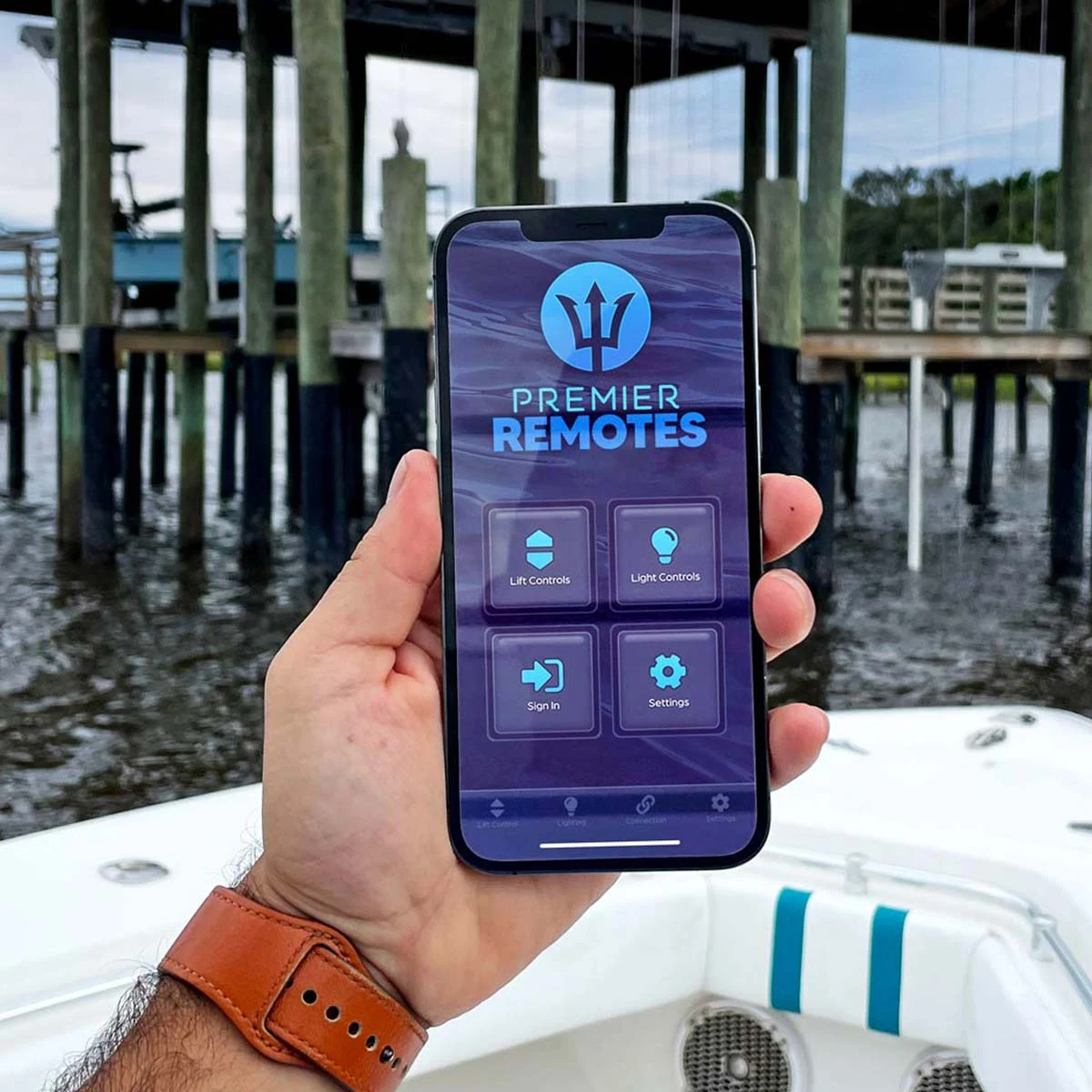 Premier Remotes app home screen on a phone held above a boat deck